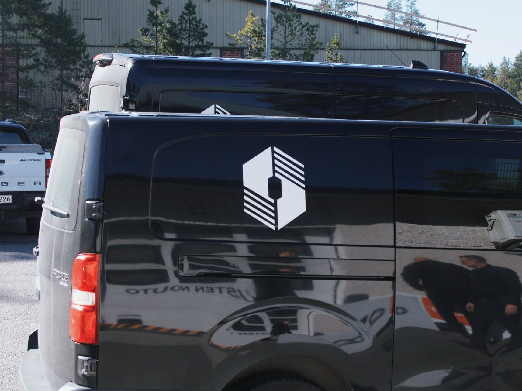 HuoltoTeamin musta pakettiauto, jonka kyljessä on yrityksen logo